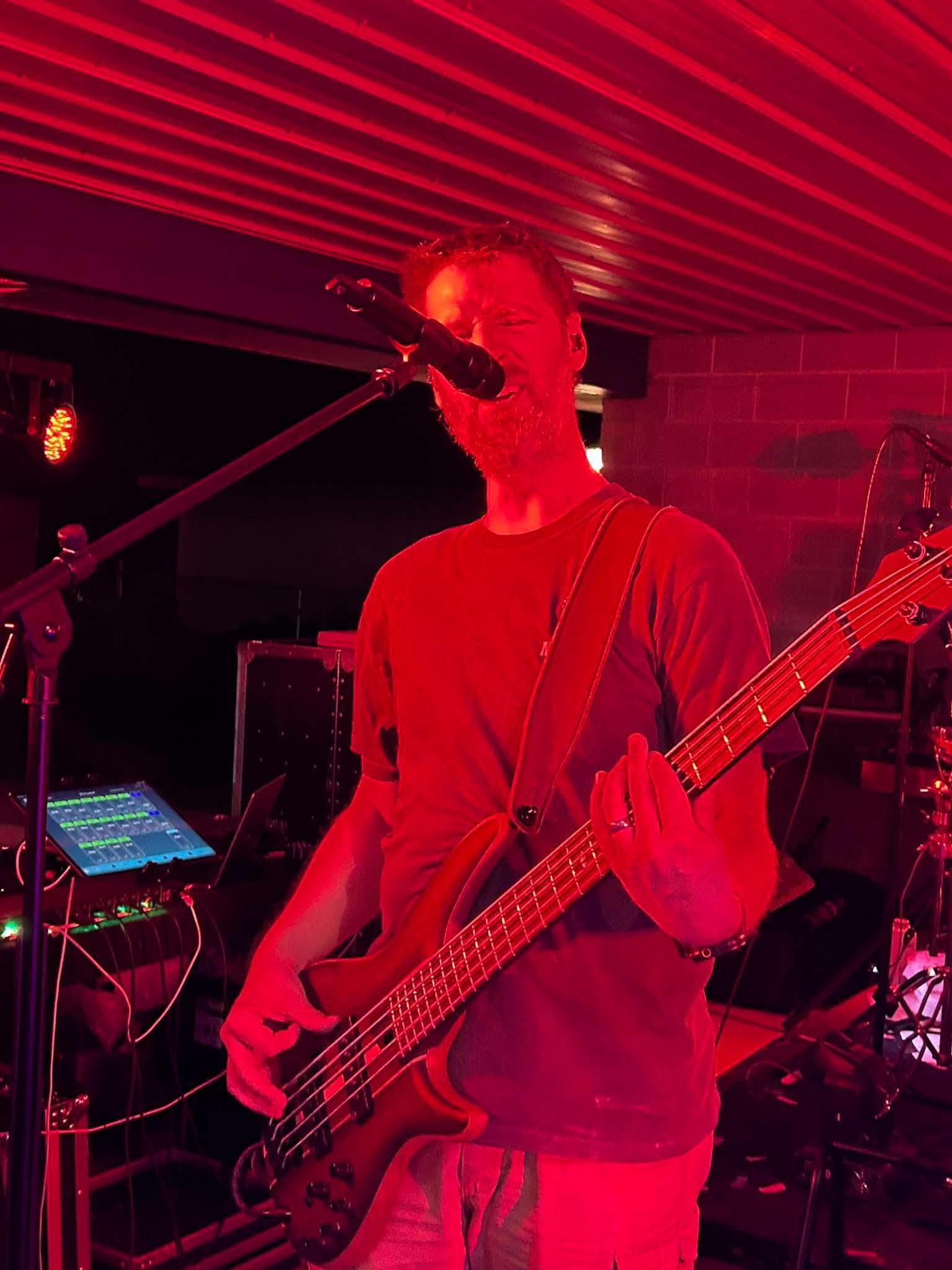 Jon Hatter playing bass and singing under red stage light